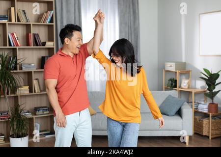 Happy korean spouses having fun at home, dancing Stock Photo