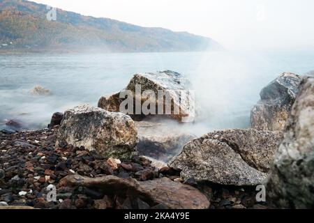The waves of Lake Baikal break on the coastal rocks Stock Photo