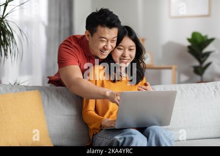 Positive korean man and woman using computer at home Stock Photo