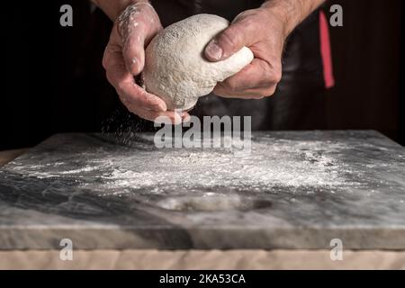Man preparing pizza, dough on marble table. Stock Photo