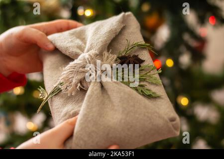 Furoshiki made from natural linen. Children's hands hold eco-friendly gift wrapping in the traditional Japanese furoshiki style on the background of a Stock Photo