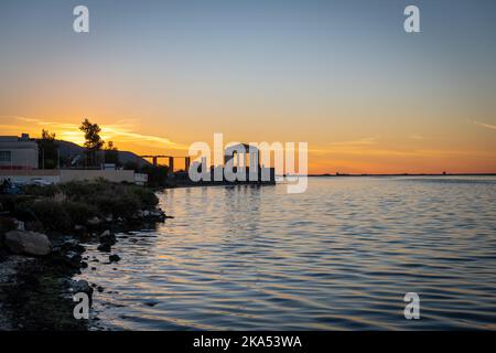 Sunset over a salt flat with golden orange light reflected on the water. Stock Photo