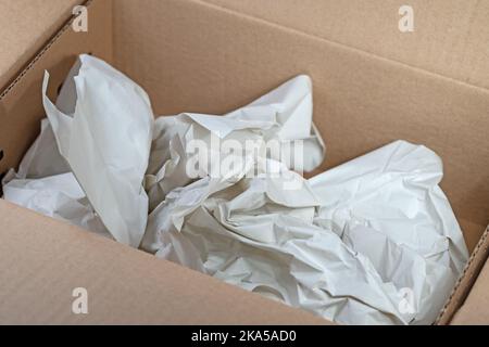 Empty cardboard box with crumpled wrapping paper Stock Photo