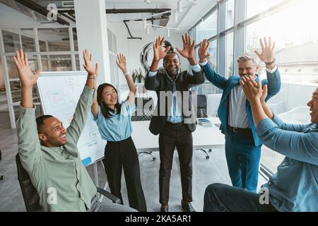 Group of happy businessmen raised their hands up after finishing work Stock Photo