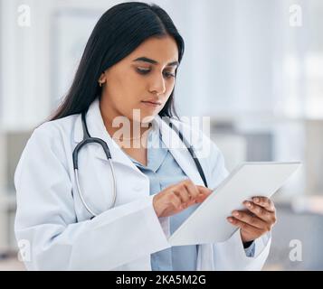 Health, healthcare and doctor on tablet in hospital working on patient records, researching medicine and planning schedule. Medical professional Stock Photo