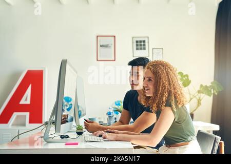 They make a great team. two young creative businesspeople working on a computer in their office. Stock Photo