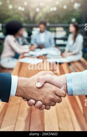 Theyve reached a new agreement. Closeup shot of two unrecognizable businessmen shaking hands with their colleagues in the background. Stock Photo