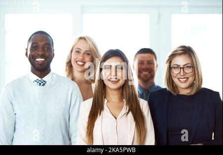 They have come a long way together. Portrait of a group of confident work colleagues standing together against a white background. Stock Photo