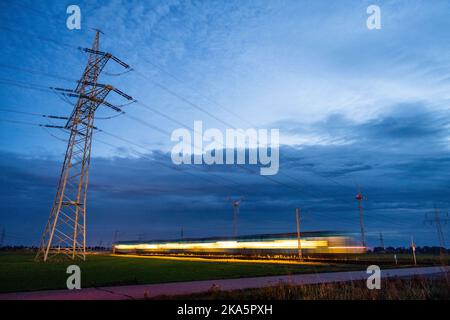 Landesbergen, Germany. 01st Nov, 2022. A train passes an electricity pylon in the early hours of the morning. Chancellor Scholz has announced key points for relieving the burden on citizens and companies in the energy crisis. Credit: Lino Mirgeler/dpa/Alamy Live News Stock Photo