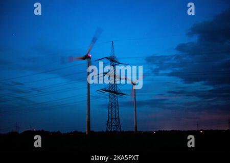 Landesbergen, Germany. 01st Nov, 2022. An electricity pylon standing before sunrise on a road in front of two wind turbines. Chancellor Scholz has announced key points for relieving the burden on citizens and companies in the energy crisis in the near future. Credit: Lino Mirgeler/dpa/Alamy Live News Stock Photo
