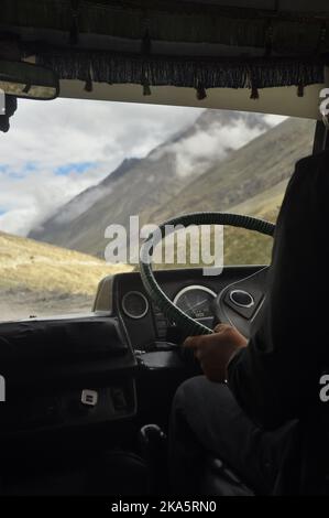 Unrecognized person driving passenger van (tempo traveller) in Manali-Leh highway with beautiful mountains view during summer season. Stock Photo