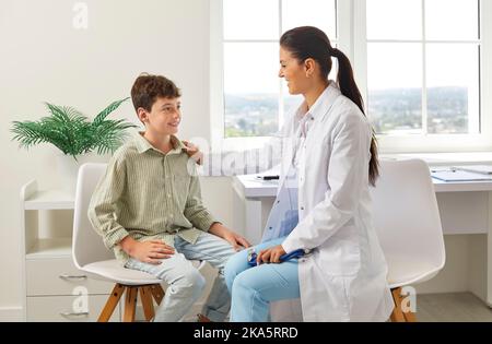 Happy preteen boy receives support from friendly female pediatrician during doctor's visit. Stock Photo