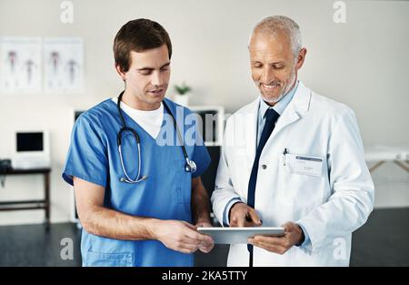 Gaining some insights from the world online. two medical practitioners using a digital tablet in a hospital. Stock Photo