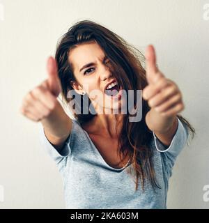 Im cool times two. Studio shot of an attractive young woman showing thumbs up. Stock Photo