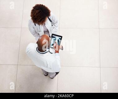 They will make the best decision for your health. High angle shot of two young doctors having a discussion over a digital tablet inside of a hospital. Stock Photo