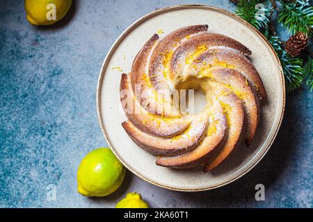 Traditional lemon cake with powdered sugar and zest, dark blue background, top view, copy space. Christmas dessert. Stock Photo