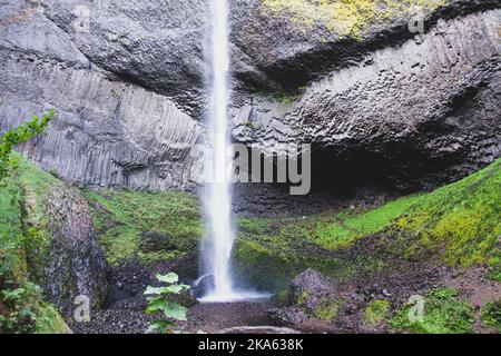 Latourell Waterfall in Oregon, with gray textured rock face and moss growing along the end of the waterfall. Stock Photo