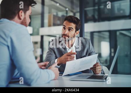 Some have opinions, the successful have data. two young businessmen using a laptop while going through paperwork together in a modern office. Stock Photo