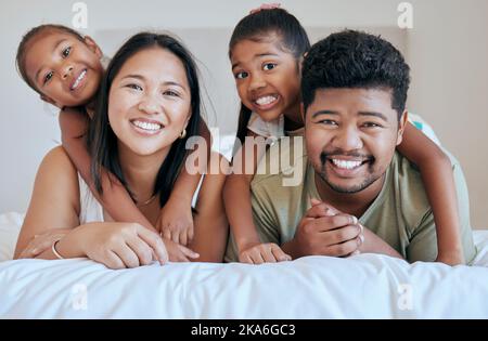 Happy family, bed and girl with mother, father and sister in a bedroom for fun, bond and rest together. Face, portrait and mexican family hug, smile Stock Photo