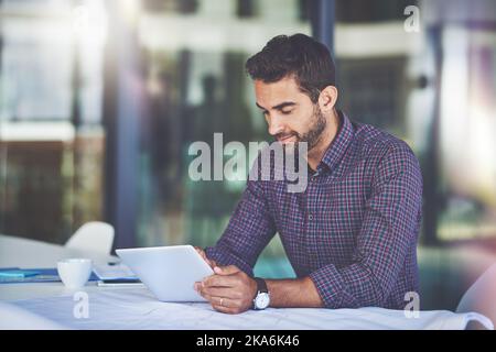 On top of his work. a handsome young businessman using a digital tablet in an office. Stock Photo