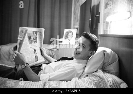 Edinburgh, Scotland - January 1965.  Roald 'Kniksen' Jensen has become a professional footballer in Scotland with Heart of Midlothian football club. Here he lies on the bed in his hotel room at the Clarendon hotel, reading the newspaper. Photo by his fiancé on the nightstand Stock Photo