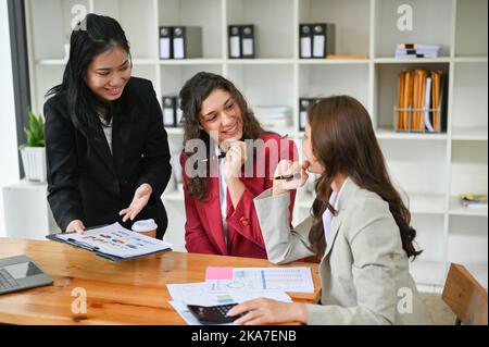 Diverse businesspeople cooperating in the office, Two attractive millennial caucasian businesswomen working with an Asian female colleague, brainstorm Stock Photo