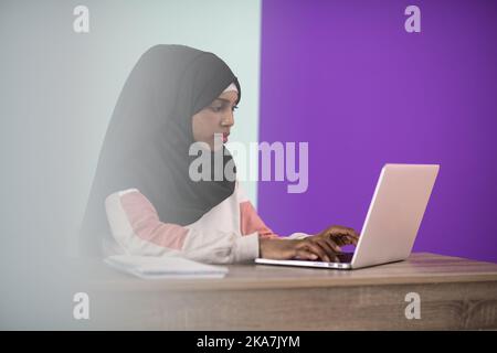 afro girl wearing a hijab is disappointed and sad sitting in her home office and using a laptop Stock Photo