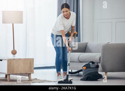 Woman, vacuum machine and cleaning the floor in the living room in home. Happy latino cleaner doing housework, housekeeper or job in a clean lounge Stock Photo