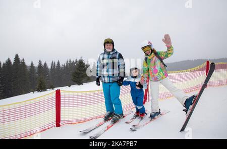 cheerful friendly family of three stands on the ski slope, parents and son in ski equipment. Sports education. Active winter recreation, healthy lifes Stock Photo