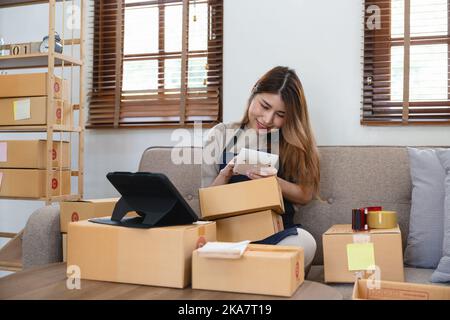 Asian woman freelancer sme business online shopping working with parcel box at home - SME business online and delivery concept Stock Photo