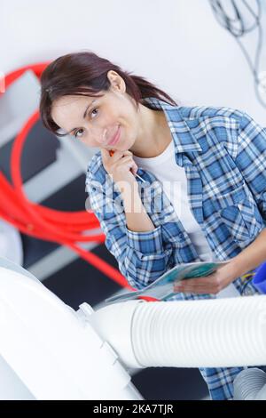 female plumber servicing central heating boiler Stock Photo