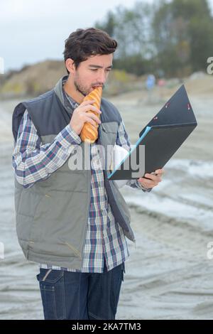 contractor on construction site eating a baguette sandwich Stock Photo