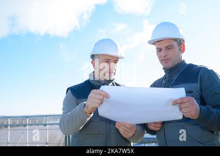 two engineers checking the architectural plan outdoors Stock Photo