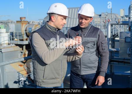 two engineers in uniform and helmets talking outdoors Stock Photo