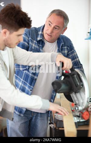 student and teacher in carpentry class using circular saw Stock Photo