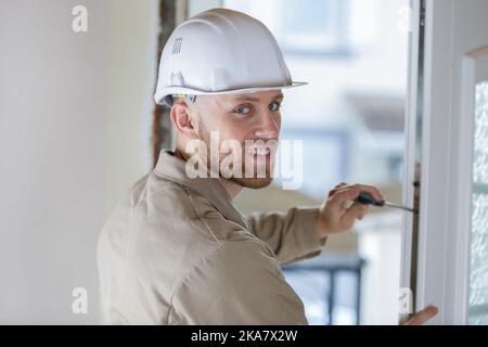 smiling male builder is fixing a window Stock Photo