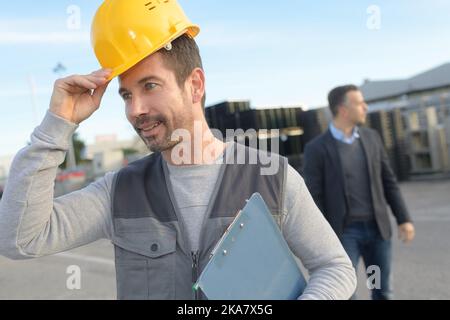worker putting his hardhat and holding clipboard Stock Photo