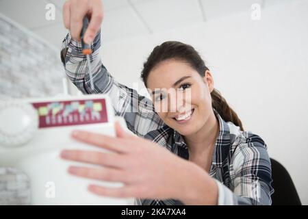 woman repairing sewing machine with a screwdriver Stock Photo