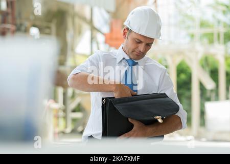 man in suit and construction helmet looking for paper Stock Photo