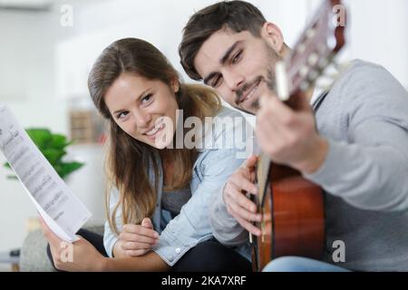 handsome man teaching girlfriend how to play the guitar Stock Photo