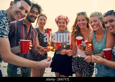 Ending the day with some sparkle. young people hanging out at the beach. Stock Photo