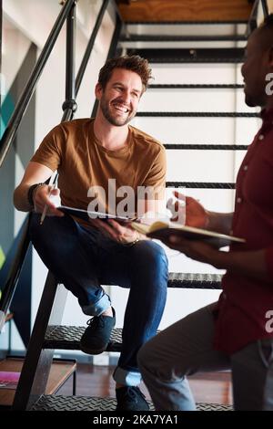 Advice is always welcome. two designers discussing something in an office. Stock Photo