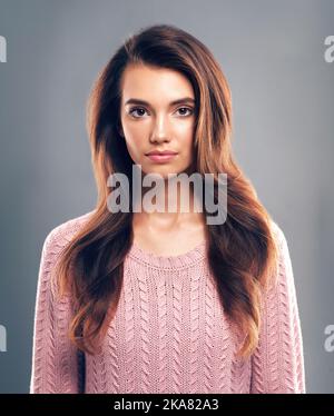 Simply stunning. Studio shot of a beautiful young woman posing against a gray background. Stock Photo