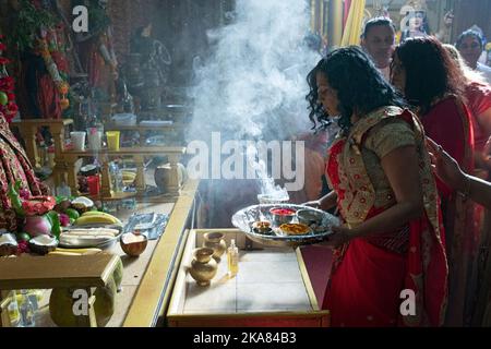 Devout Hindu devotees make offerings to their deities in a Hindu tempple in Ozone Park, Queens, New York City. Stock Photo