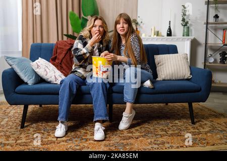 Women with surprised faces watching tv at home on the couch Stock Photo