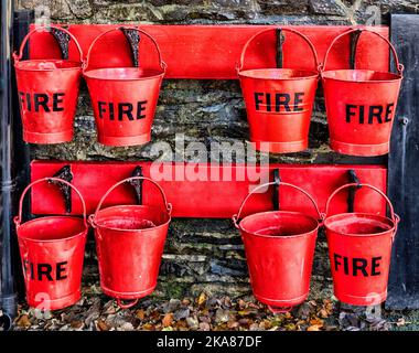 Heritage red Fire buckets hanging on railway station platform.at Woody Bay Station on the Lynton and Barnstaple Railway, Lynton, North Devon, England. Stock Photo