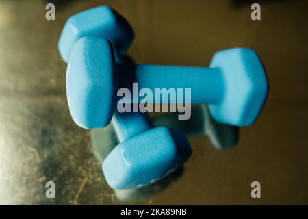 two five pound light blue hand weights on reflective golden surface Stock Photo