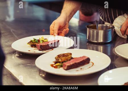 A closeup shot of the hands of the chef preparing a fine dinner in the kitchen of a restaurant in London, England Stock Photo