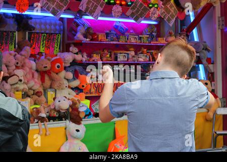 Boy shooting a gun on a rifle range trying to win prizes at a fair. Stock Photo
