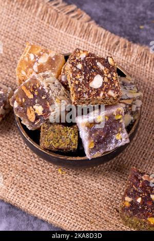 Mixed Turkish delight varieties on a dark background. Pistachio, hazelnut and fruit flavored Turkish delights. close up Stock Photo